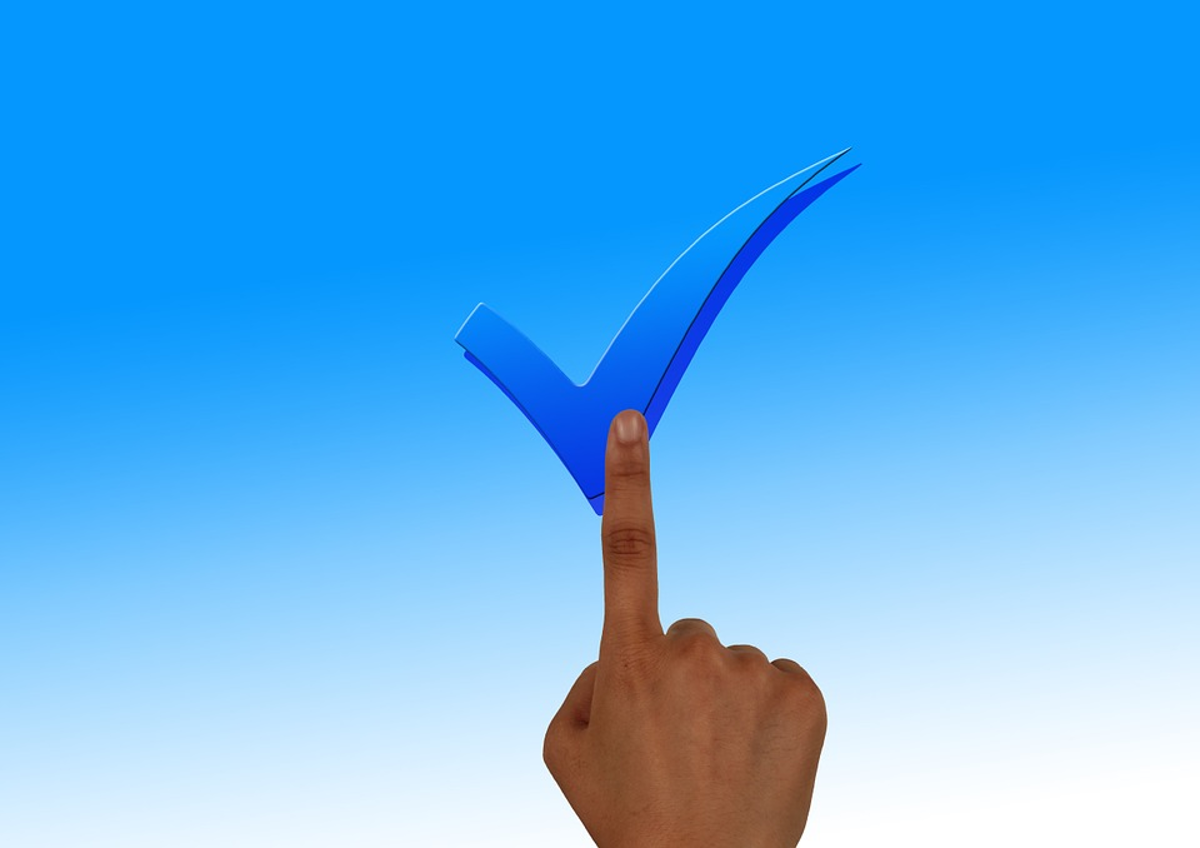 Hand die wijst naar een blauw vinkje
